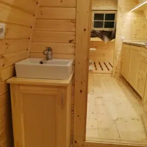 Wooden camping pod, bathroom washbasin and open doorway