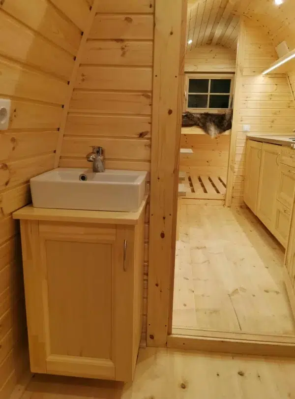 Wooden camping pod, bathroom washbasin and open doorway