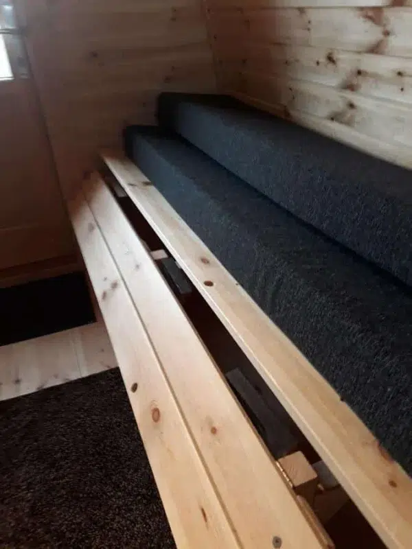 Wooden camping pod, close-up of convertible bench platform