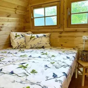 Wooden camping pod, close-up of double bed and pillows