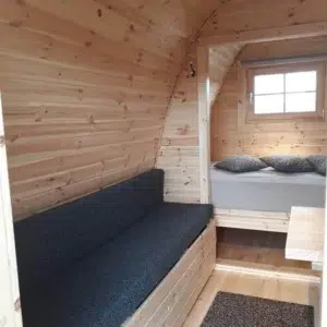 Wooden camping pod, cushioned bench and rear sleeping area