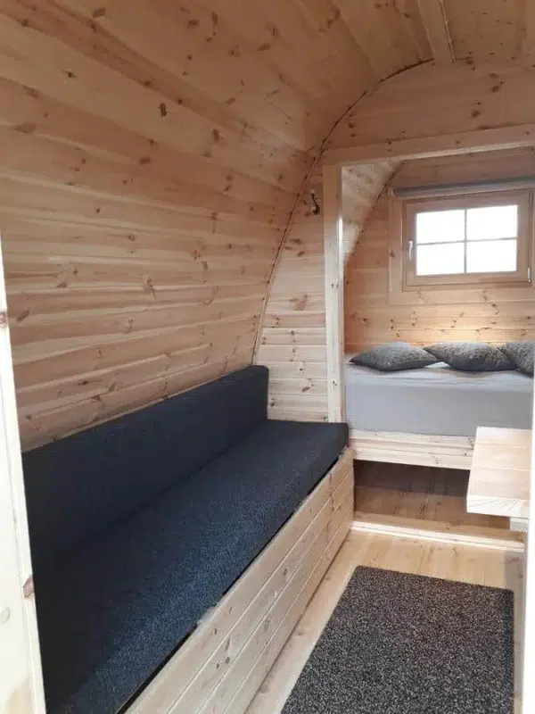 Wooden camping pod, cushioned bench and rear sleeping area