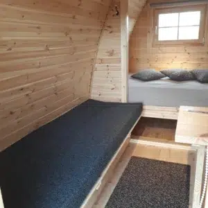 Wooden camping pod, cushioned bench and rear sleeping area