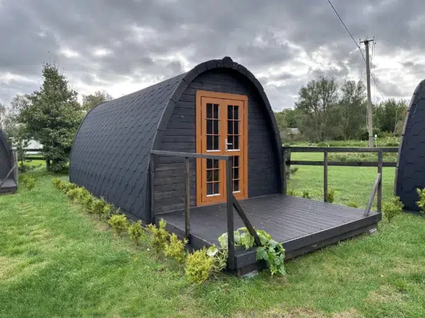 Wooden camping pod, dark exterior with front deck