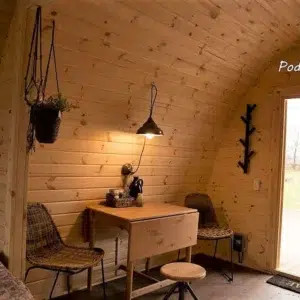 Wooden camping pod, dining table beside glazed entrance