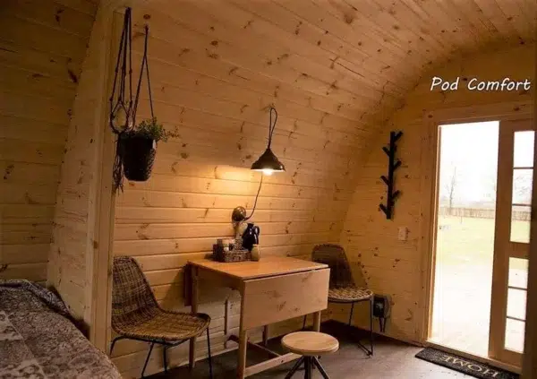 Wooden camping pod, dining table beside glazed entrance