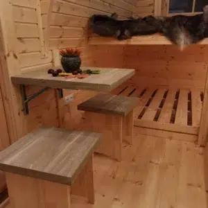 Wooden camping pod, dining table beside raised sleeping platforms