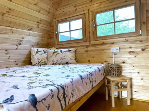 Wooden camping pod, double bed beneath paired windows