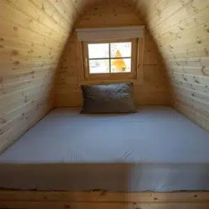 Wooden camping pod, double sleeping platform beneath window