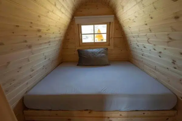 Wooden camping pod, double sleeping platform beneath window