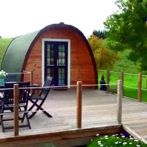 Wooden camping pod, front entrance beside furnished deck
