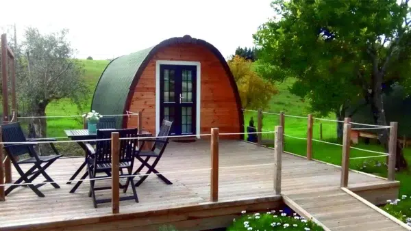 Wooden camping pod, front entrance beside furnished deck