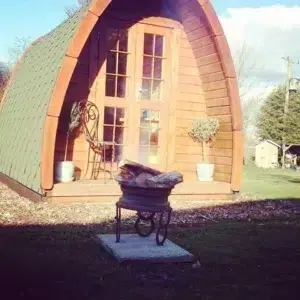 Wooden camping pod, front entrance beside an outdoor grill