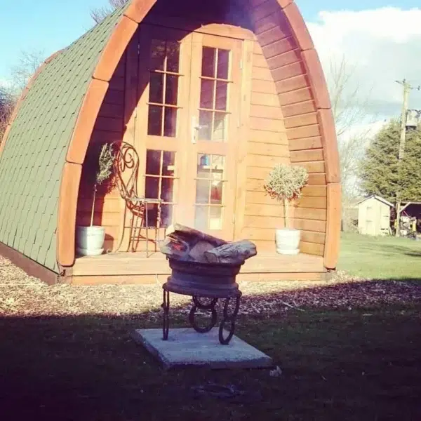 Wooden camping pod, front entrance beside an outdoor grill