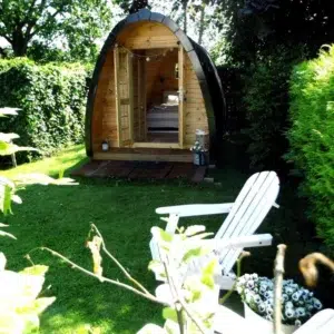 Wooden camping pod, front entrance in a leafy garden