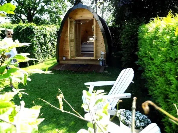 Wooden camping pod, front entrance in a leafy garden