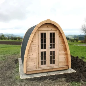 Wooden camping pod, front exterior beside an open field