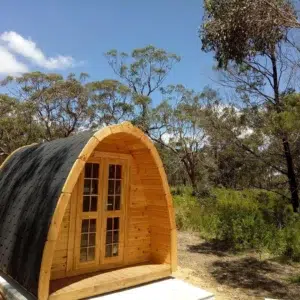 Wooden camping pod, front exterior surrounded by trees