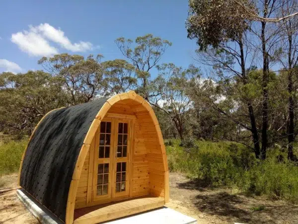 Wooden camping pod, front exterior surrounded by trees