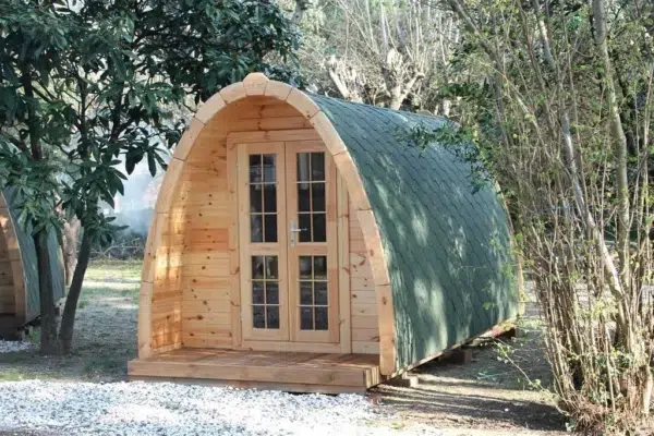 Wooden camping pod, front and side exterior with green roof