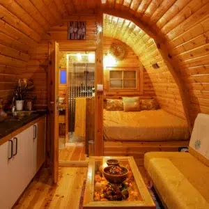 Wooden camping pod, furnished interior with kitchenette and bed
