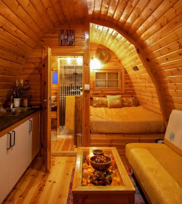 Wooden camping pod, furnished interior with kitchenette and bed