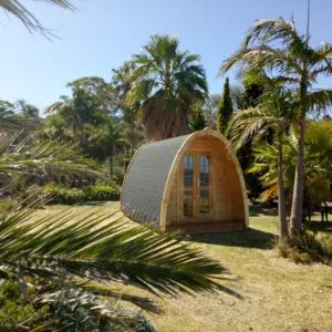 Wooden camping pod, garden installation among palm trees
