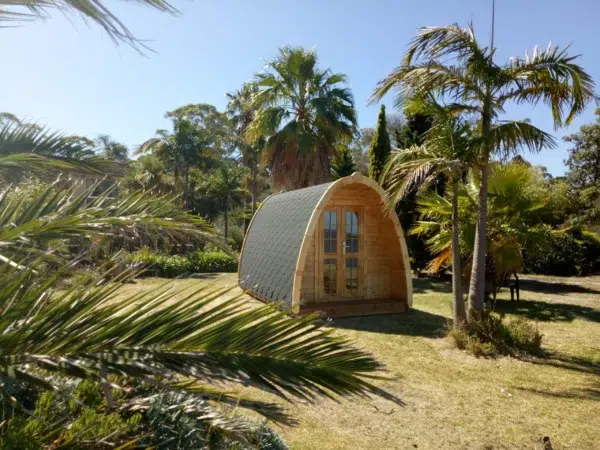 Wooden camping pod, garden installation among palm trees