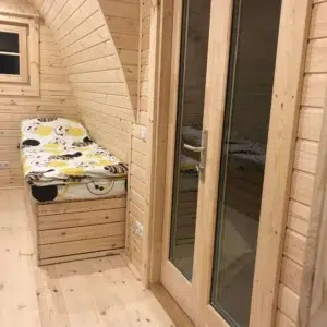 Wooden camping pod, glazed internal door beside a bed
