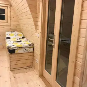 Wooden camping pod, glazed internal partition beside sleeping area