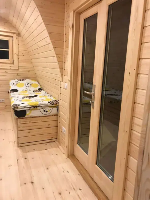 Wooden camping pod, glazed internal partition beside sleeping area