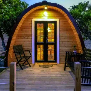 Wooden camping pod, illuminated entrance and furnished deck