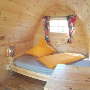 Wooden camping pod, interior bed and small wooden table
