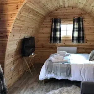 Wooden camping pod, interior bed and wall-mounted television