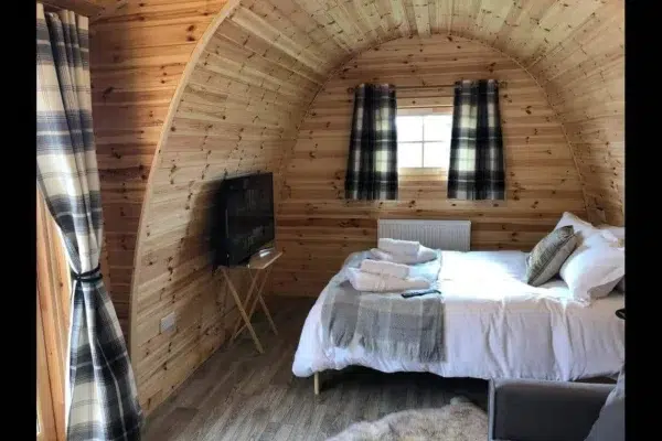Wooden camping pod, interior bed and wall-mounted television