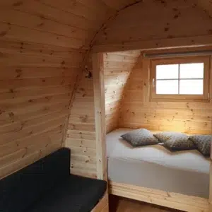 Wooden camping pod, interior seating beside a separate sleeping area