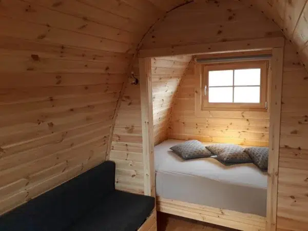 Wooden camping pod, interior seating beside a separate sleeping area