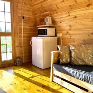 Wooden camping pod, interior seating, refrigerator and entrance doors