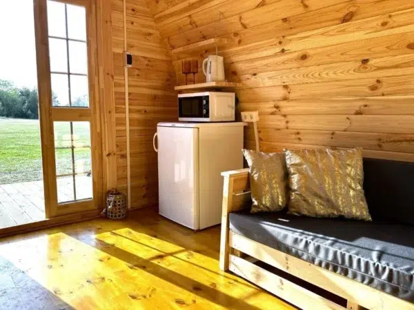 Wooden camping pod, interior seating, refrigerator and entrance doors