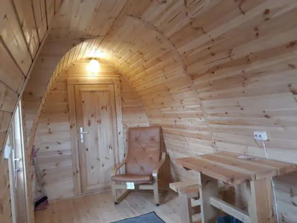 Wooden camping pod, interior table, chair and wooden partition