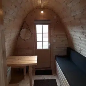 Wooden camping pod, interior table and cushioned bench