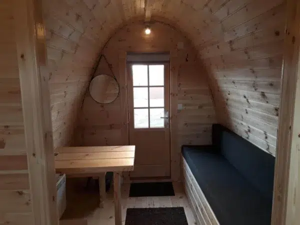 Wooden camping pod, interior table and cushioned bench