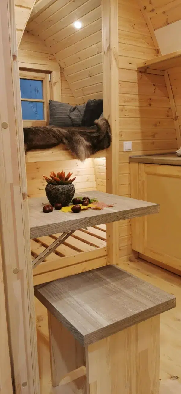Wooden camping pod, interior table and raised sleeping area