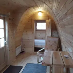 Wooden camping pod, interior with table and toilet compartment