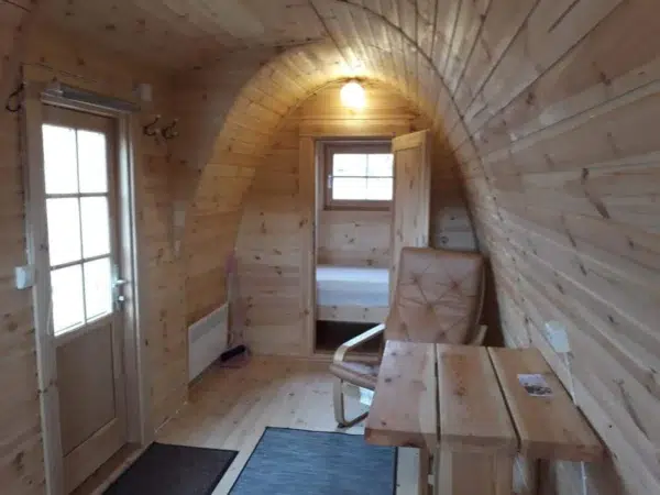 Wooden camping pod, interior with table and toilet compartment