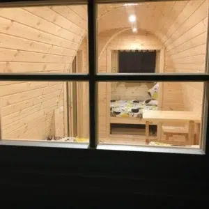 Wooden camping pod, interior viewed through an exterior window