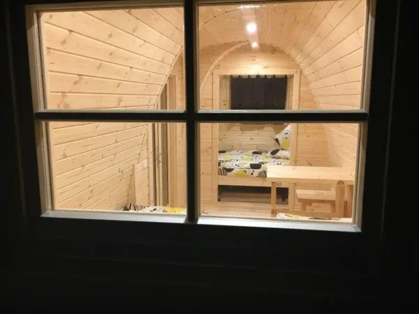 Wooden camping pod, interior viewed through an exterior window