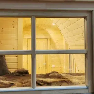 Wooden camping pod, interior viewed through an exterior window