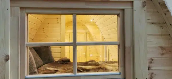 Wooden camping pod, interior viewed through an exterior window