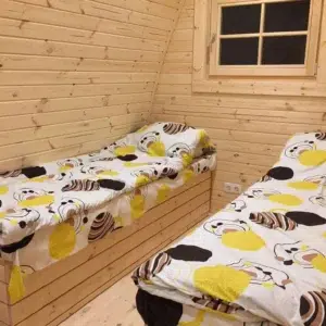 Wooden camping pod, interior twin beds beneath a window